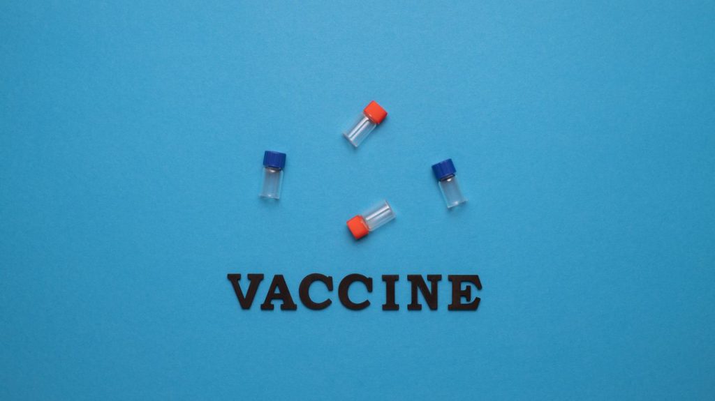 Three small vials and the word 'VACCINE' on a blue background, representing vaccination and health.